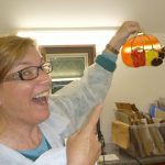 A student happily shows off the glass suncatcher that she's just finished making