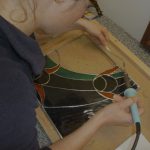 In a copper foiled stained glass class Kent student solders her first stained glass window panel