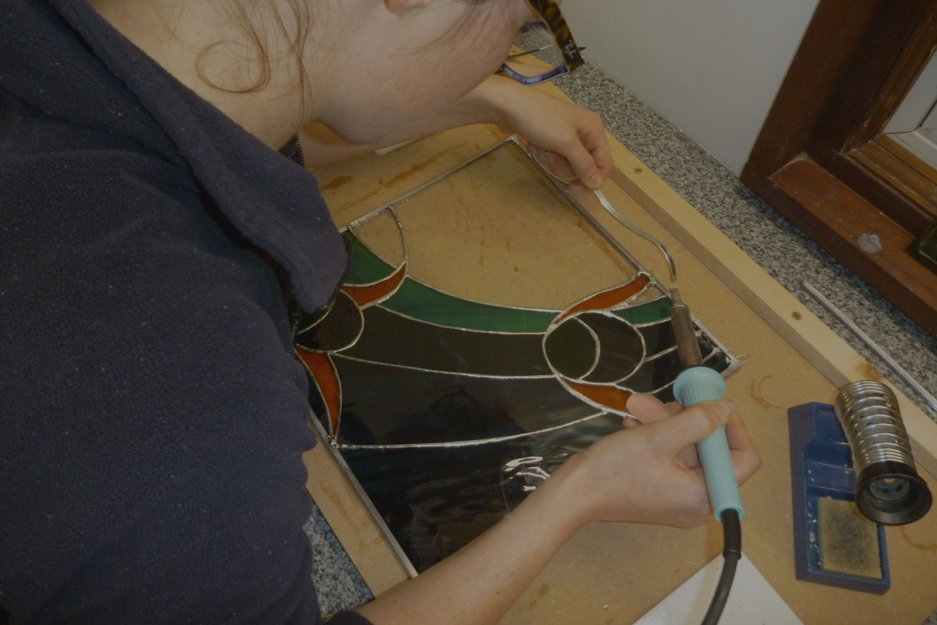 In a copper foiled stained glass class Kent student solders her first stained glass window panel