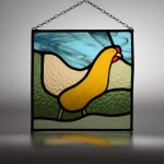 Stained glass picture of a chicken, with hanging chain attached