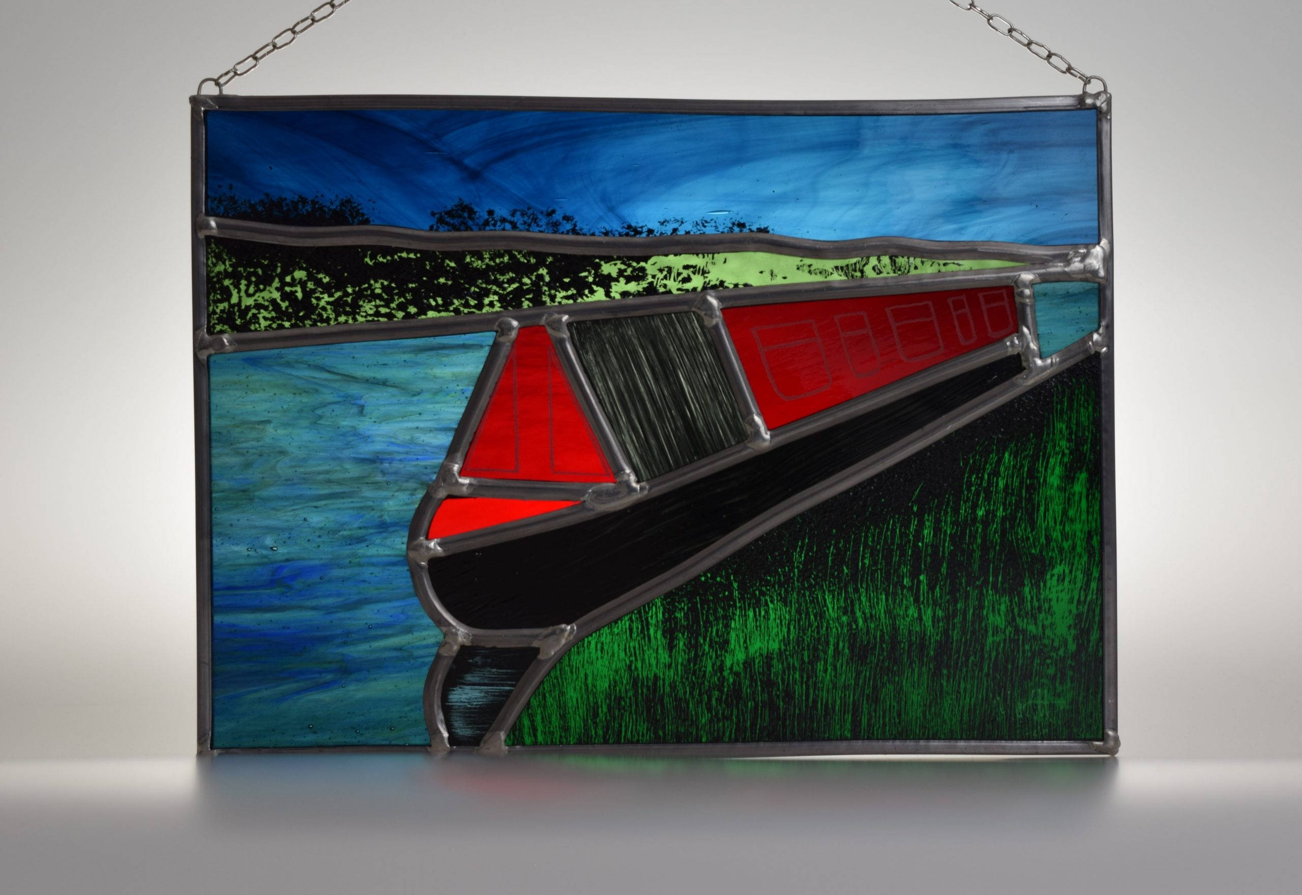 A stained glass picture of a narrowboat moored on the River Weaver, close to the Trent and Mersey canal, in Cheshire