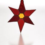 Stained glass six pointed star in two shades of red glass with gold glass hexagon in the centre