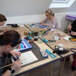 Four visitors to Creative Retreats and Holidays' glass studio glue their stained glass mosaics before finishing them with grout